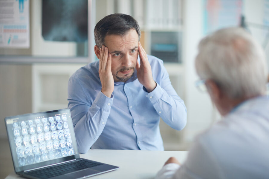 Paciente consultando dolor de cabeza con neurocirujano en consultorio médico especializado